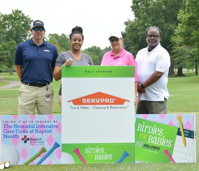 marketing team standing beside golf tournament sign