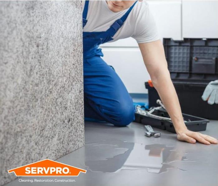 Standing water on floor with man next to toolbox and SERVPRO logo