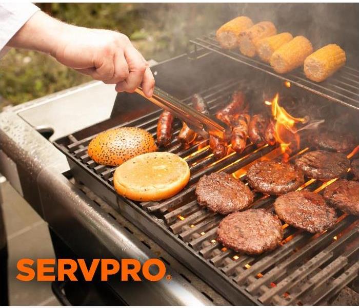 man grilling food outside with SERVPRO logo 